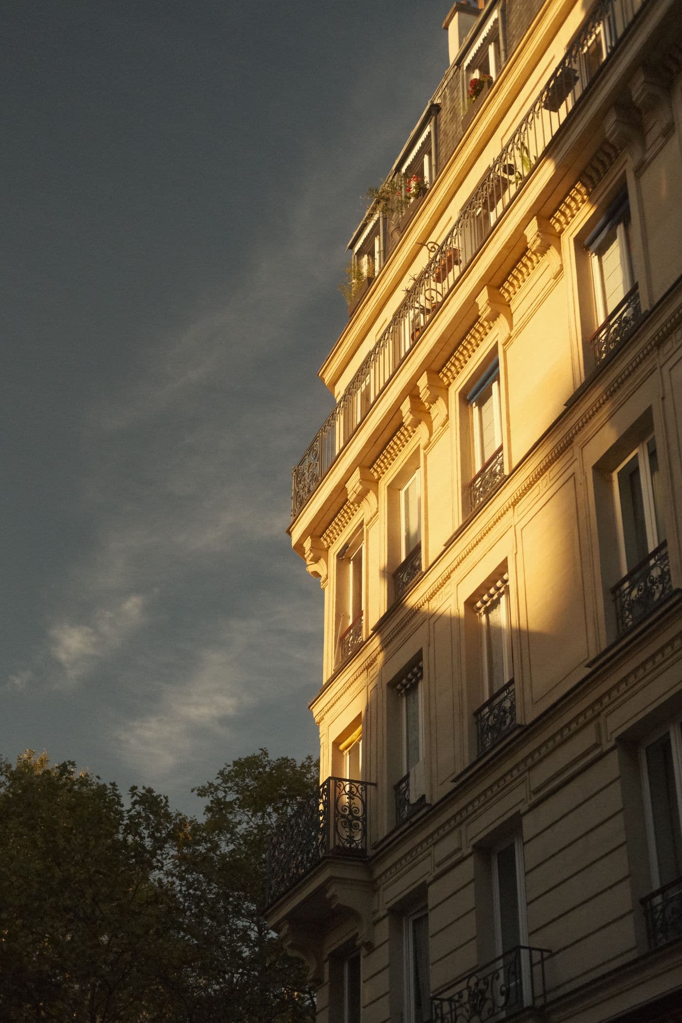 Façade haussmannienne en pierre de taille illuminée par la lumière dorée du soir