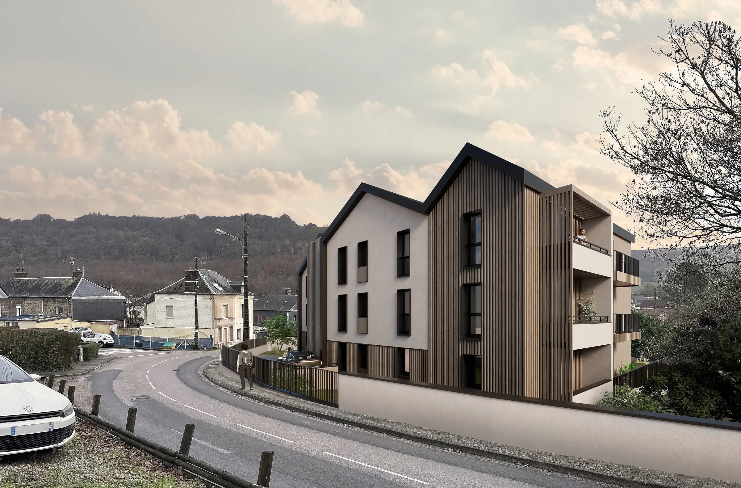 Perspective de La Fontaine depuis la route en contrebas : deux volumes à pignon, façades enduit clair et bardage bois vertical sombre, balcons en retrait, avec le coteau boisé de Montville en arrière-plan