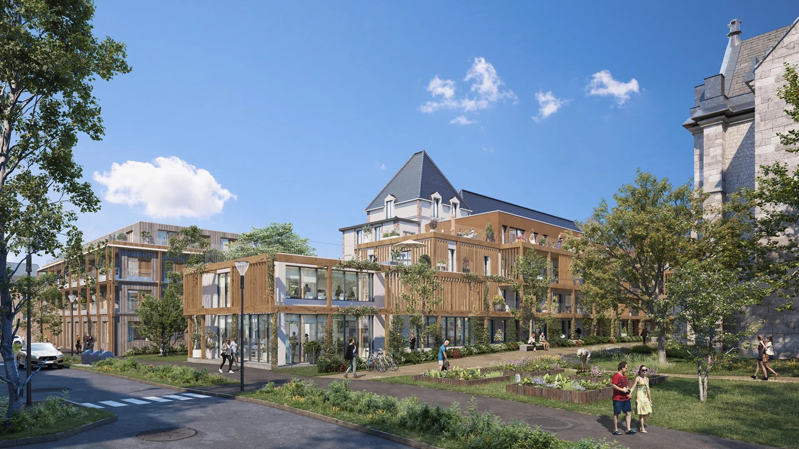 Le Domaine vu depuis l’allée : bâtiments neufs à bardage bois et pergolas, une villa ancienne à toiture d’ardoise réhabilitée au centre, la chapelle en pierre sur la droite, jardins partagés au premier plan