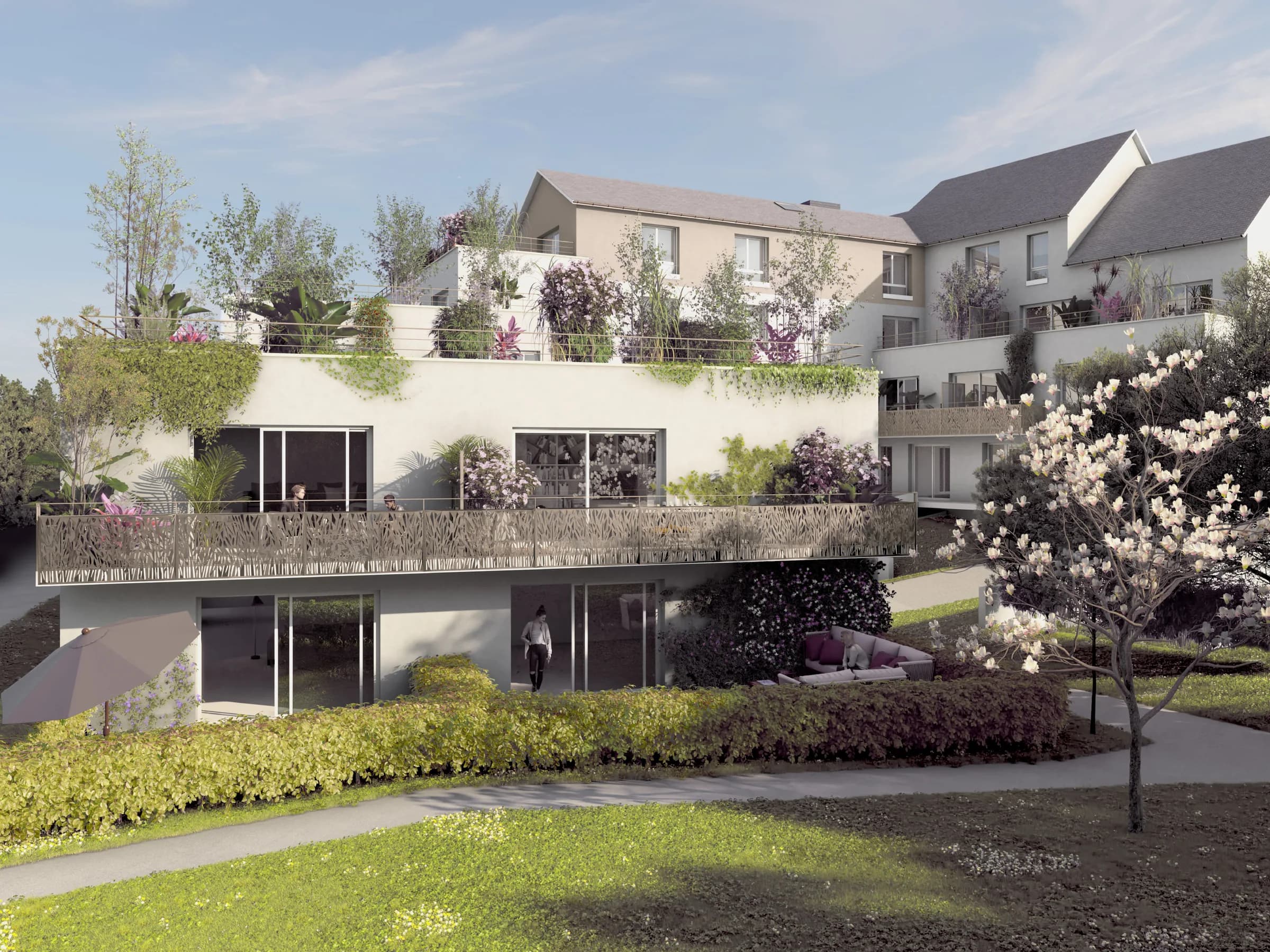La résidence côté jardin : terrasses en gradins largement plantées, garde-corps ajourés, magnolia en fleurs et pelouse au premier plan