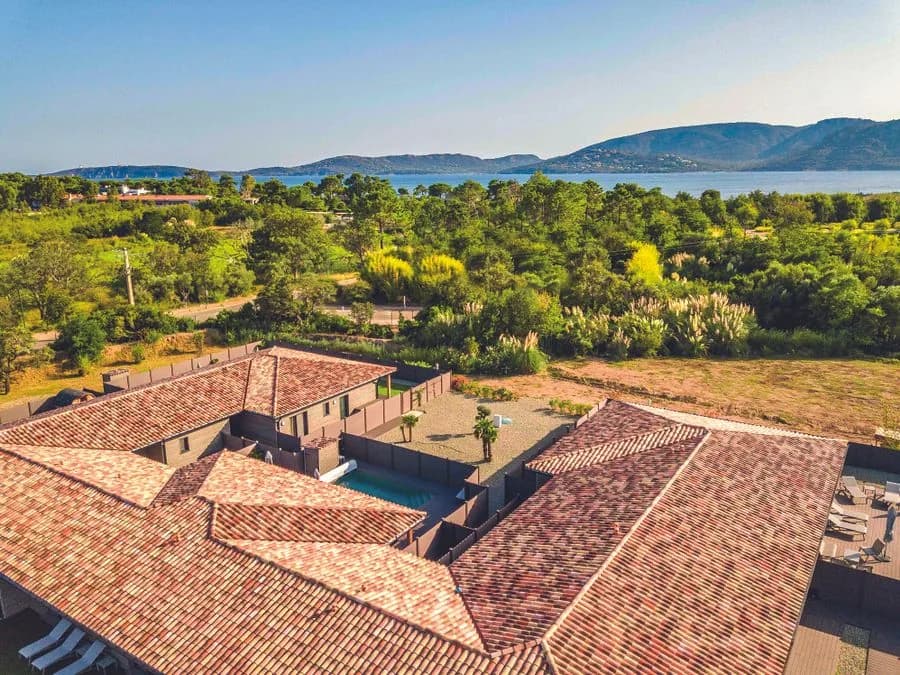 Vue aérienne de Vesna Rossa : villas à toiture de tuiles rondes autour de leurs piscines, la pinède puis le golfe de Porto-Vecchio et les montagnes à l’horizon